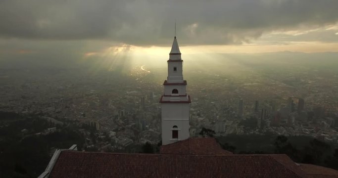 Sunset aerial flying behind Monserrate Church in Bogota Colombia with the city below