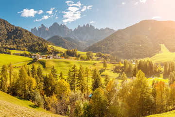 Famous travel destination in Italian Dolomites Funes valley. Val Di Funes and Santa Magdalena village during autumn with rocky Alps at the background