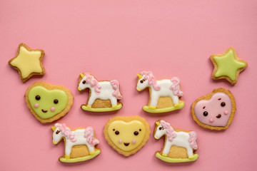 Unicorn and heart shaped sugar cookies decorated with pastel royal icing on pink background