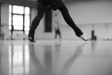 Legs of ballerina dancing in pointe in warm socks at rehearsal in the hall