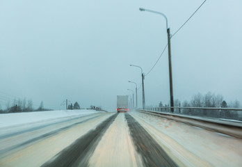 Truck drives with tail and stop lights on the winter road in a snow storm in the  twilight  when...