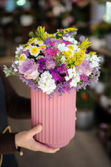 Beautiful flower arrangement with roses, limonium sinuatum, chrysanthemum flowers and other plants in the woman florist hands.
