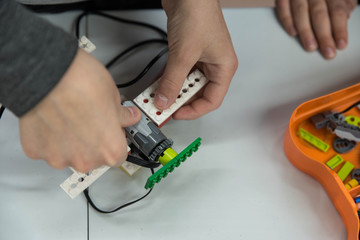 Group of kids building robot constructor from the plastics details programmed on the computer, at robotics school lesson. Education, children, technology, science and futuristic concept. E-learning. 