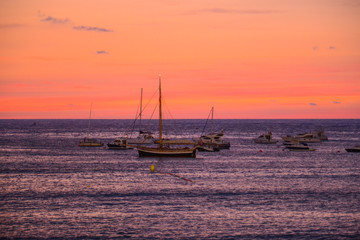 Atardecer sobre el mar, con unos barcos tipo veleros