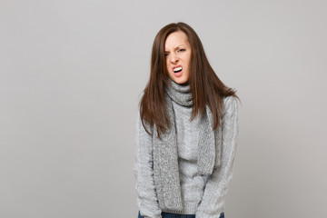 Prostrate exhausted irritated young woman in gray sweater, scarf isolated on grey background studio...