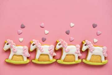 Unicorn shaped sugar cookies decorated with pastel royal icing on pink background