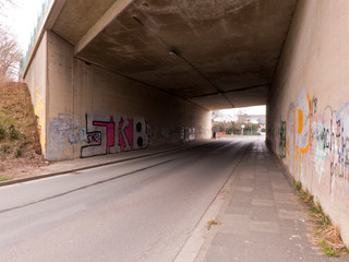 Eine Unterführung unter der Autobahn. Die Wände sind mit Graffiti bemalt.
