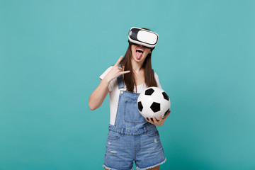Funny girl football fan in headset hold soccer ball showing tongue, horns up gesture isolated on...