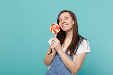 Portrait of dreamful smiling young woman in denim clothes looking up holding colorful round...