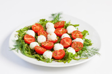 Greek salad on the plate, mozzarella cheese and cherry tomato, white background