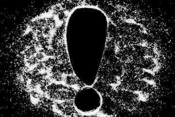Exclamation mark sign symbol drawing by finger on white snow salt powder on black background. Tick concept with place for text. Copy space.