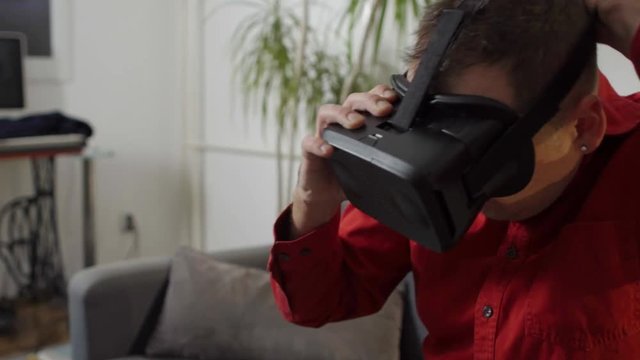 man in red shirt  putting on and enjoying vr at home virtual reality googles 
