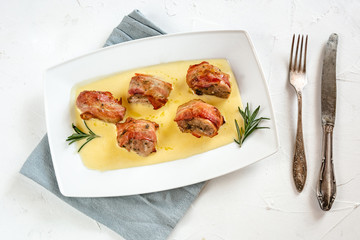 Baked pork tenderloin wrapped in bacon and served in a cheese sauce with rosemary