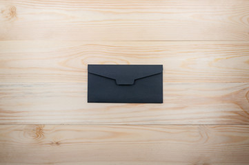 Black single envelope on a natural wooden table. top view
