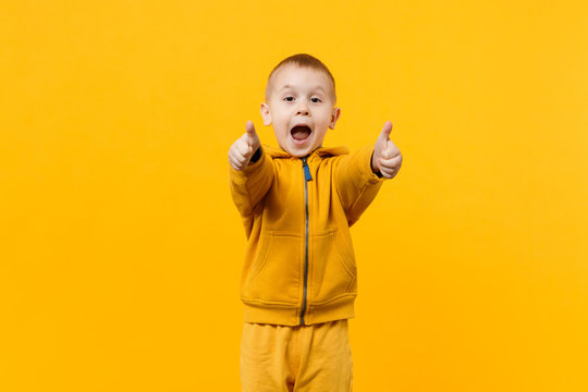 Little cute kid boy 3-4 years old wearing yellow clothes isolated on bright orange wall background, children studio portrait. People sincere emotions, childhood lifestyle concept. Mock up copy space.