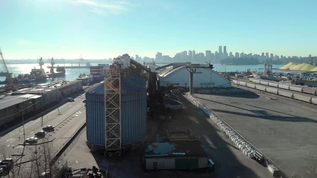 An aerial view of silos in the North Vancouver cargo terminal and trainyard with a view of downtown Vancouver.