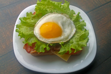 Preparing a sandwich with scrambled eggs, bacon and cheese