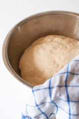 Yeast and white wheat flour dough after rising in bowl for homemade traditional German Kaiser rolls or Austrian Vienna rolls on white wooden background