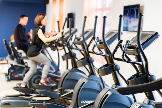 People train on elliptical cross trainers in fitness room