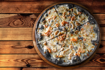 Cuttlefish ink pizza, on a wooden board, top view