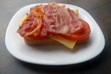 Preparing a sandwich with scrambled eggs, bacon and cheese