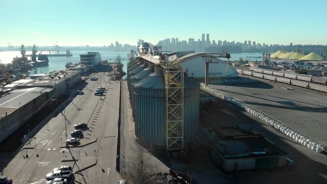 An aerial view of silos in the North Vancouver cargo terminal and trainyard with a view of downtown Vancouver.