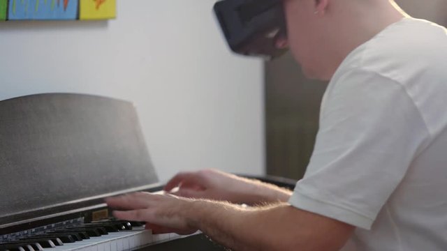 Man playing piano with VR virtual reality googles 
