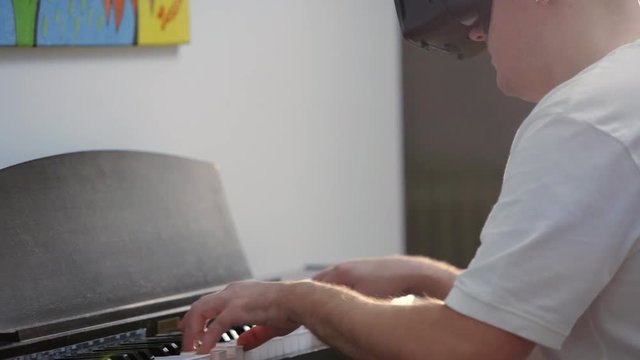 Man playing piano with VR virtual reality googles 
