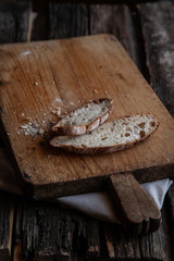 Fresh bread slice and cutting knife on rustic table