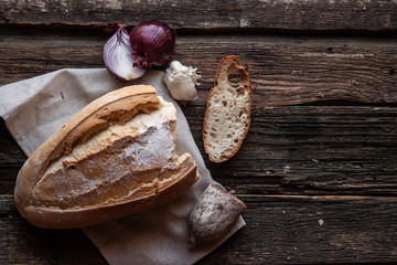 Fresh bread slice and cutting knife on rustic table