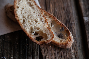 Fresh bread slice and cutting knife on rustic table