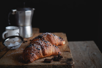 Croissant with chocolate and coffee on the wooden table