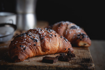 Croissant with chocolate and coffee on the wooden table
