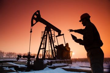 Oil Drill, field pump jack silhouette with setting sun and worker.Refinery, natural gas. Lens...