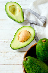 Avocado in a wooden bowl on a white wooden background