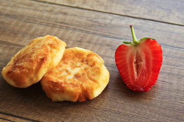 Cheesecakes on a wooden background, breakfast of cheesecakes with strawberries.