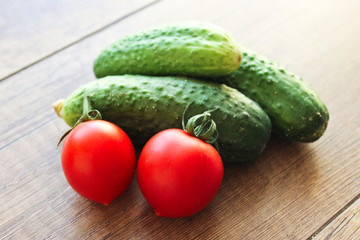 Cucumbers and tomatoes on a wooden background, vegetables.