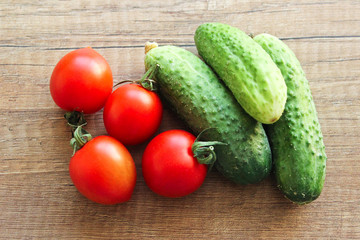 Cucumbers and tomatoes on a wooden background, vegetables.