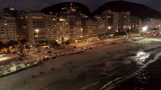 Night aerial panning wide from Copacabana Beach to ocean in Rio de Janeiro, Brazil