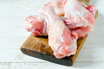 Raw uncooked chicken legs, drumsticks on wooden board, meat with ingredients for cooking
