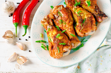 Baked chicken legs on a plate on a white wooden table