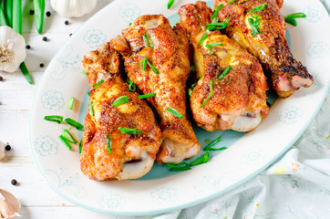 Baked chicken legs on a plate on a white wooden table