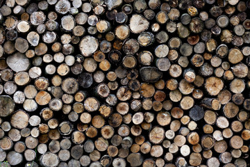 Background of dry chopped firewood logs stacked up on top of each other in a pile.