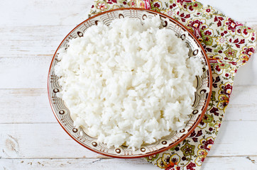 Boiled rice in a plate on a white wooden table