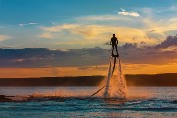 Fly board.Silhouette of a fly board rider over a river against the setting sun. 