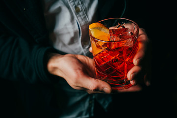 Negroni cocktail in men's hands close-up on dark background