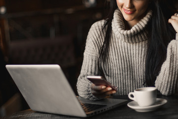 Business woman working on a laptop and drinking coffee in a cafe.