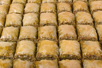 Baklava with a large pistachio cereal in a large tray close to the table