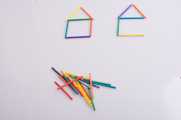 Two houses made of colorful sticks and a bunch of sticks aside. One not fully built. - 245443236