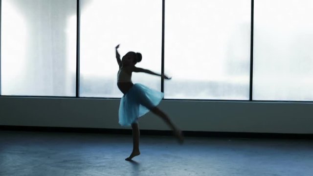 Young girl wearing ballet dress dancing barefoot in studio
